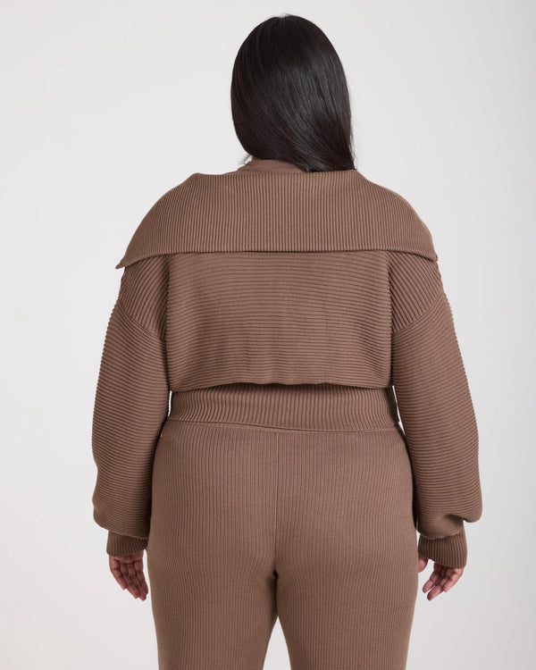 Back view of a taupe ribbed jumper with a funnel neck, showcasing the sophisticated texture and relaxed fit.