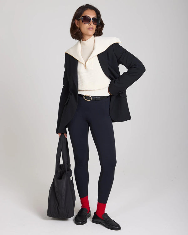 Model wearing the Sorella Ribbed Half Zip Jumper in cream styled with a black blazer and leggings.