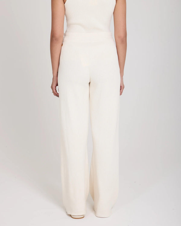 Back view of Emello Sorella Ribbed Knit Wide Leg Trousers in Cream, featuring relaxed fit and gold-finish branded details.