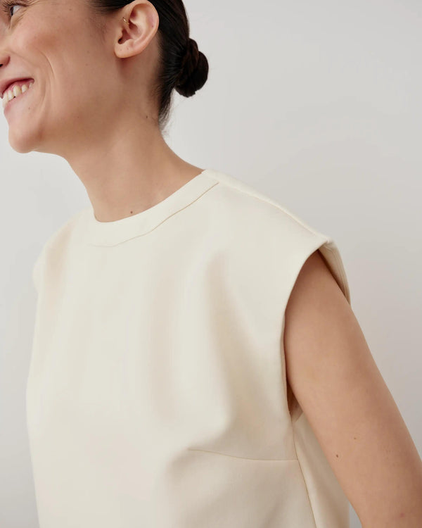 Model wearing Emello's Structured Layered Vest in cream, showcasing the sculpted, architectural lines and soft jersey underlayer.