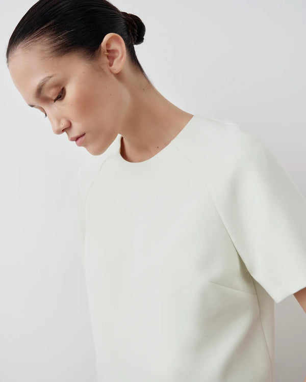 Model wearing a mist green structured short sleeve top with a sculptural silhouette from Emello.