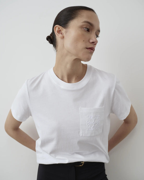 Model wearing Emello's Supima Cotton Pocket Tee in white, featuring a crew neckline and signature mirror chain-stitch embroidery on the pocket.