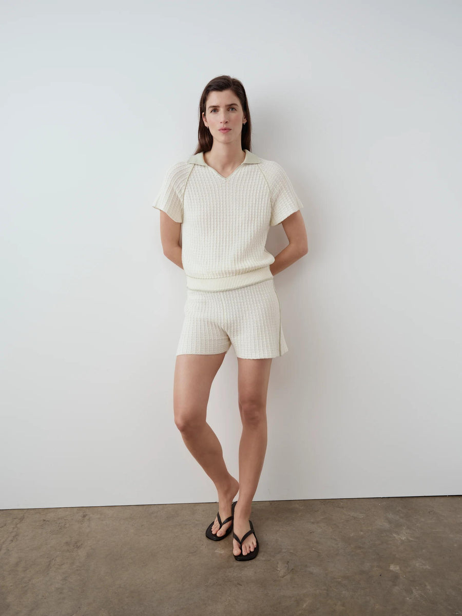 Model wearing Emello's Textured Knit Shorts in white, featuring a crochet-effect knit and contrast seams.