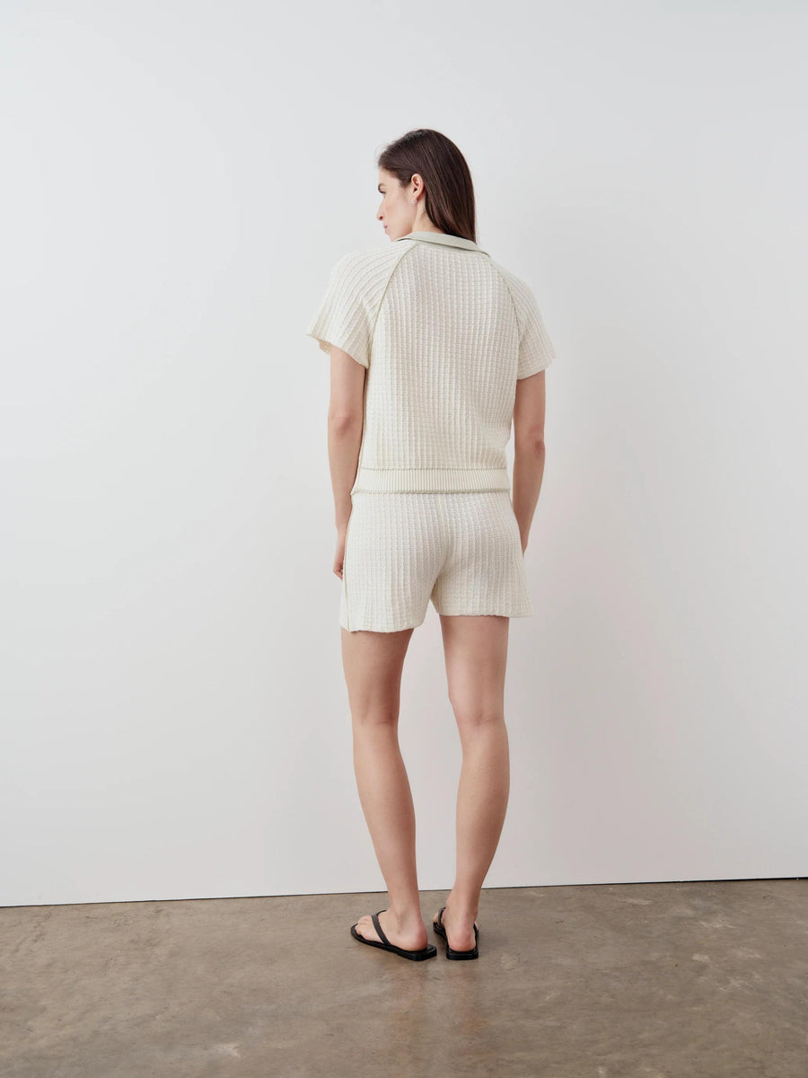 Model wearing Emello's white textured knit shorts showcasing a fluted shape and open stitch detail.