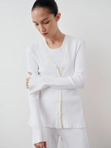 Emello Tonal Ribbed Cardigan with a clean V neckline, worn by a model, showcasing its elegant fluted cuffs and waved edges in soft white.