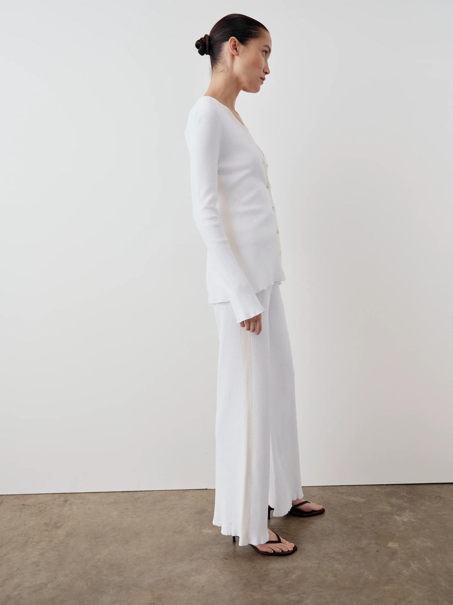 Side view of a model wearing Emello's white tonal ribbed cardigan with elongated sleeves and button front.