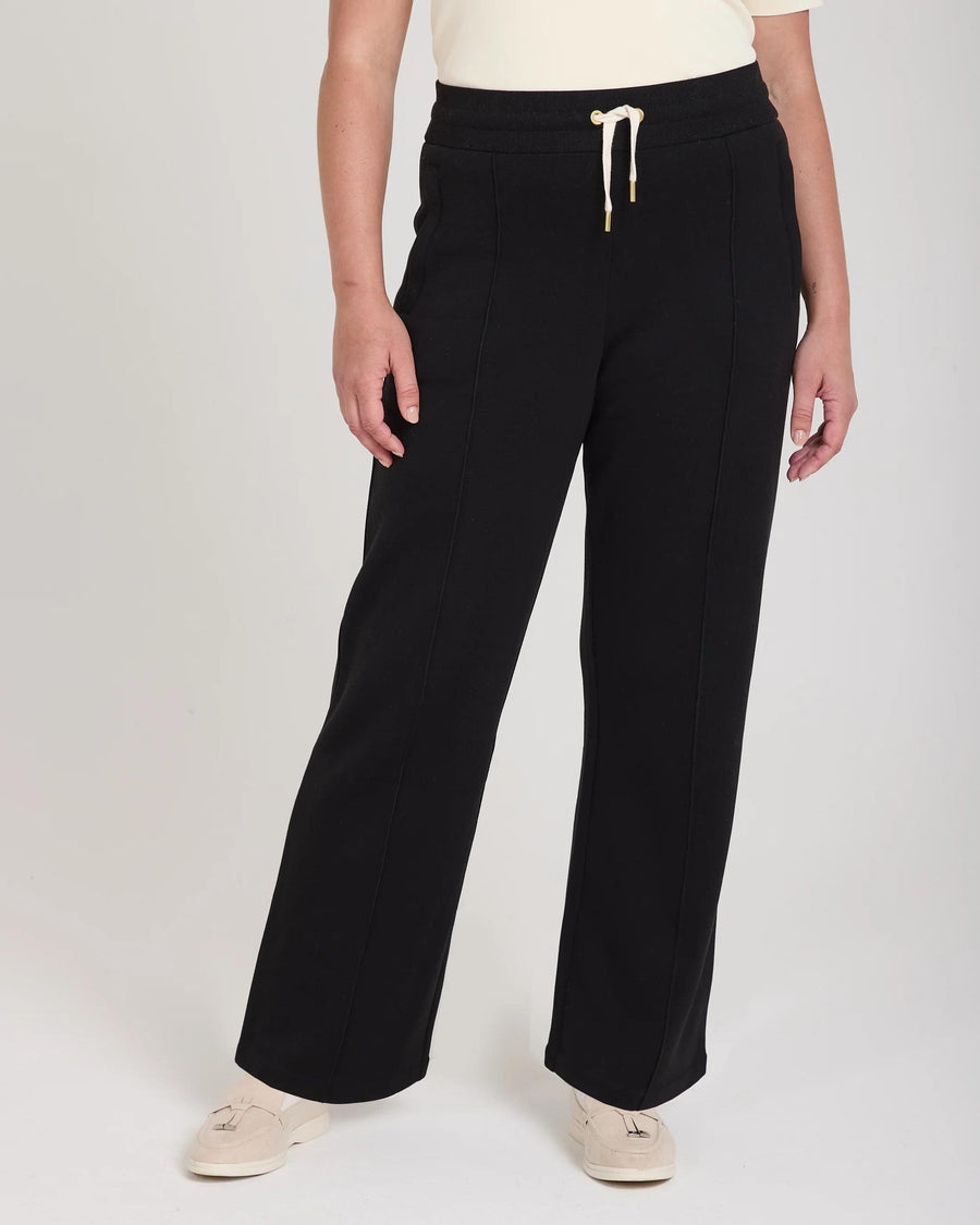 Elegant black wide-leg trousers in lyocell with gold accents and pin-tuck detailing, styled for Emello's AW2025 collection.