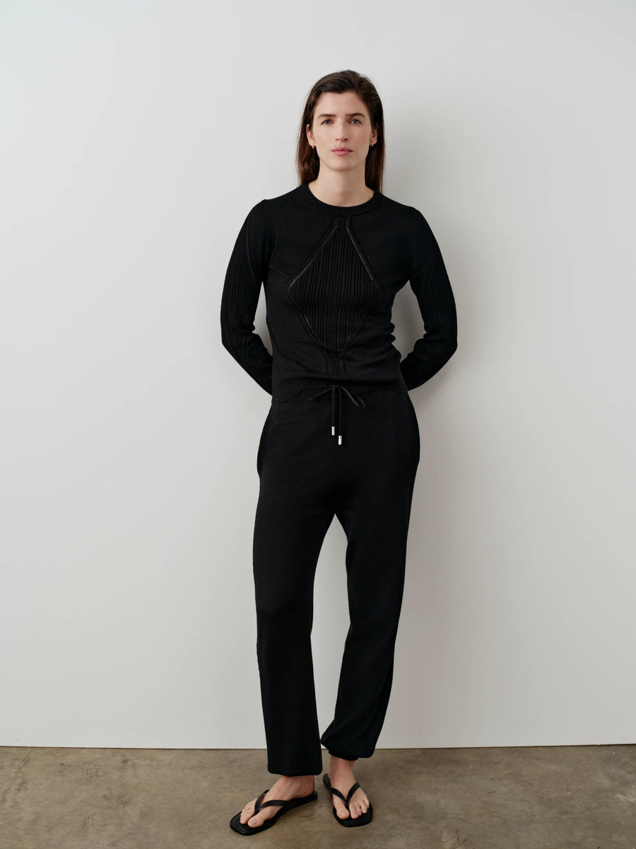 Model wearing Emello black silk blend pointelle trousers with matching top.