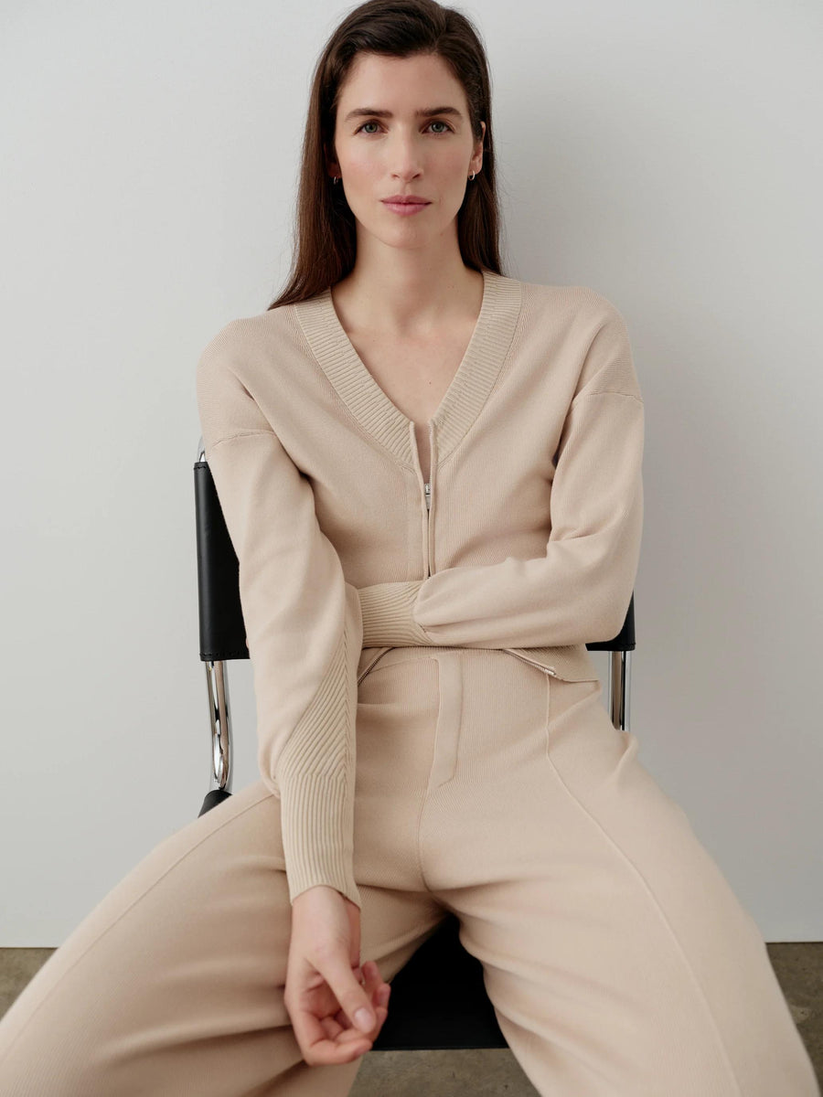 Emello V-Neck Zip Cardigan in neutral organic cotton worn by model sitting with crossed legs