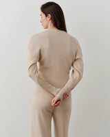 Back view of a model wearing the Emello V-Neck Zip Cardigan in a neutral tone, showcasing soft shoulders and structured waist.