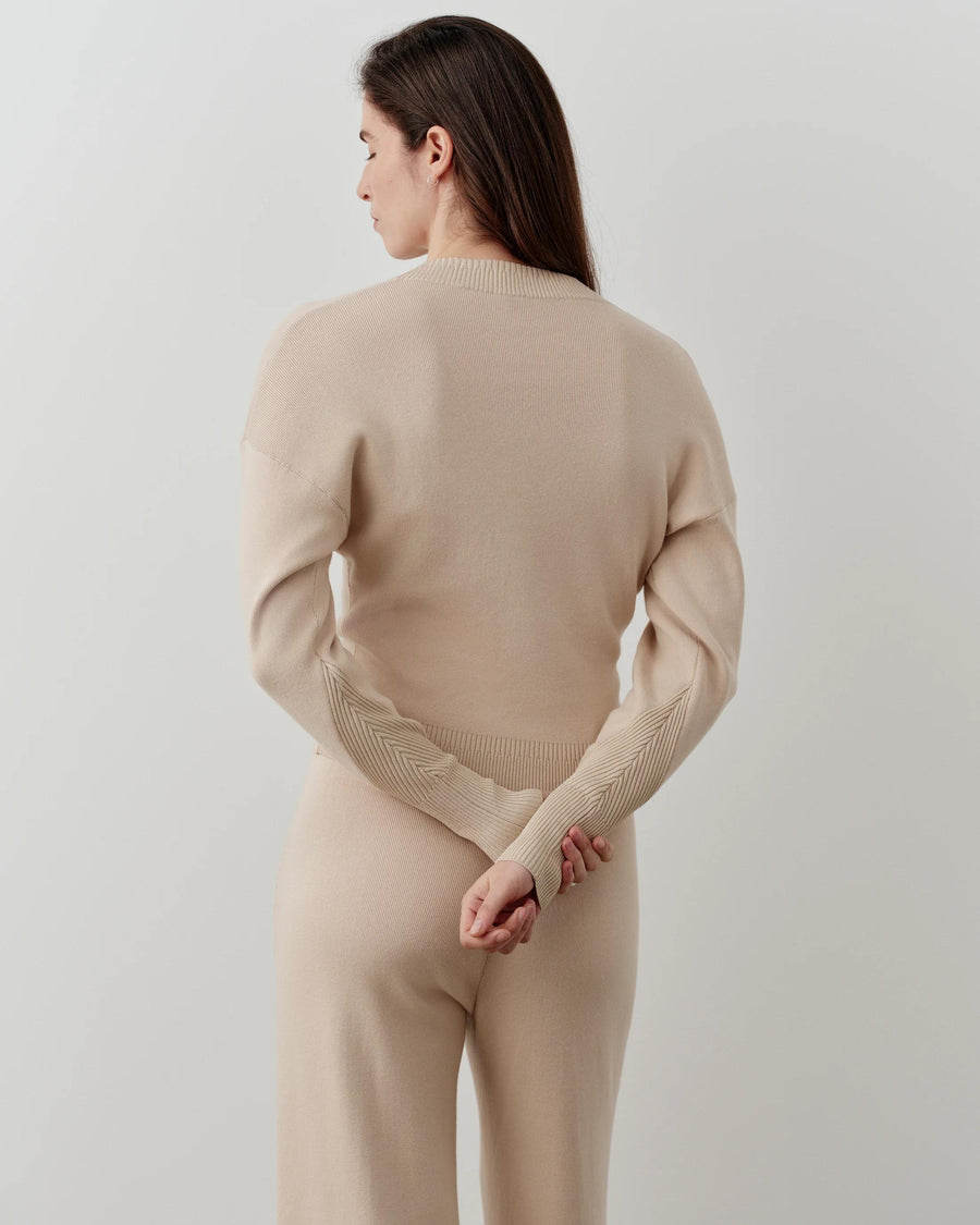 Back view of a model wearing the Emello V-Neck Zip Cardigan in a neutral tone, showcasing soft shoulders and structured waist.