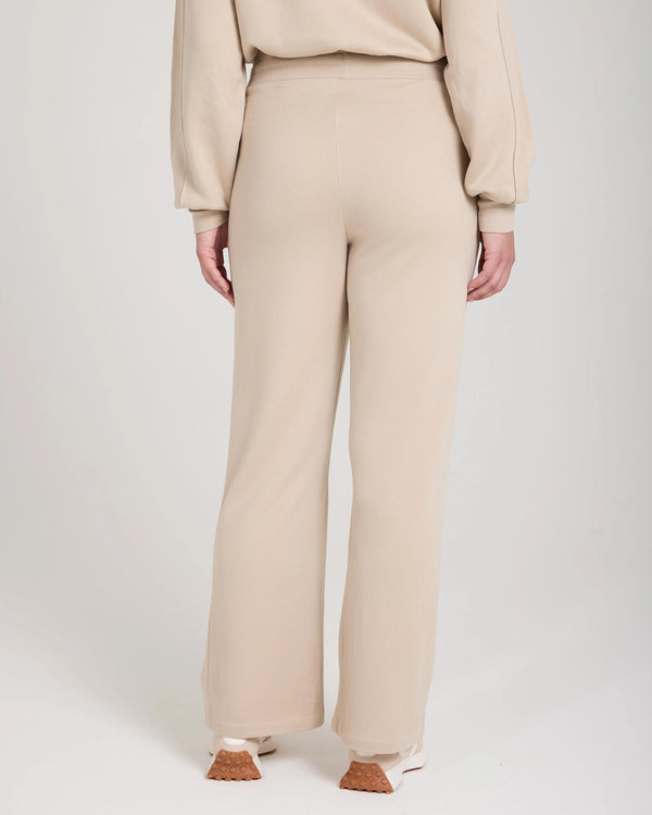 Back view of beige wide-leg fleece pants showcasing relaxed drape and elegant silhouette.
