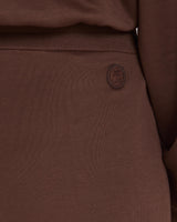 Close-up of chocolate brown Lyocell wide-leg pants with subtle embroidery, highlighting texture and refined detail.