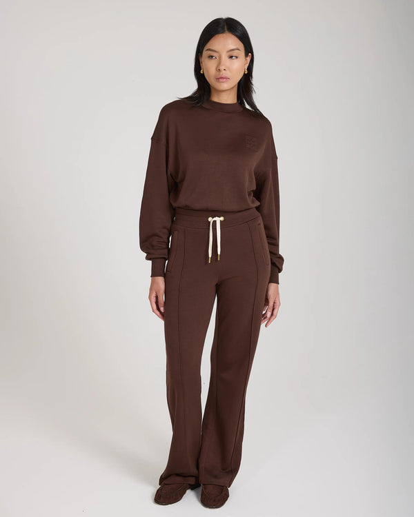 Model wearing Emello Mello Lyocell Fleece Wide Leg Pants in Chocolate, showcasing a relaxed fit with luxurious gold accents.