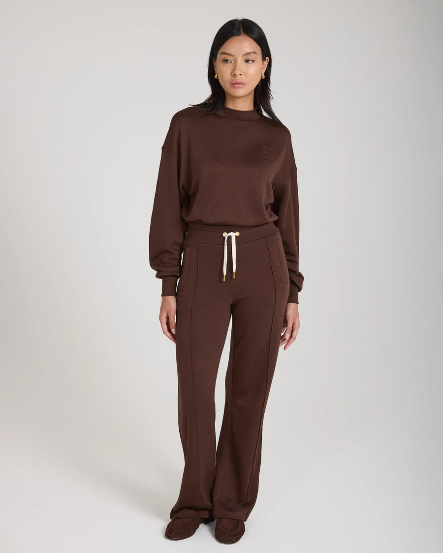 Model wearing Emello Mello Lyocell Fleece Wide Leg Pants in Chocolate, showcasing a relaxed fit with luxurious gold accents.