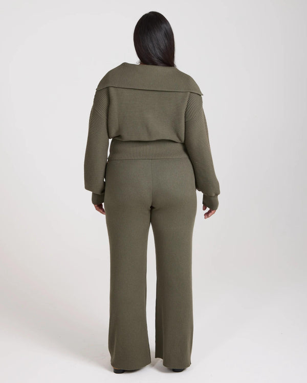 Back view of model wearing olive green ribbed knit wide leg trousers with relaxed fit.